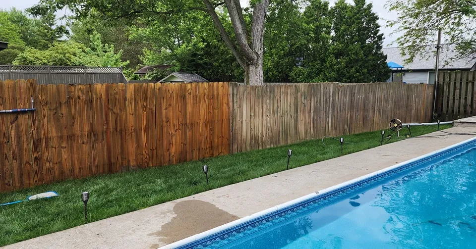 Wood fence half restored by washing, showing the clean-vs-weathered difference